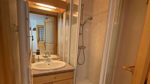 Un baño con lavabo, espejo, ducha y armarios de madera.
