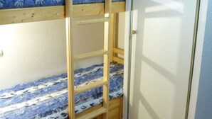 A bunk bed with a ladder, a door, and a patterned bedspread. - Charming central apartment - 4 guests (Arêches-Beaufort)