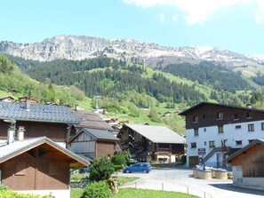 A mountain village with traditional wooden buildings, a central road, and a mountain backdrop. - Apartment pets welcome - 6 guests village center (Arêches-Beaufort)