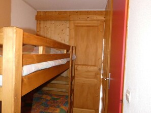 A bunk bed with a wooden headboard, a door with a handle, and a colorful patterned rug on the floor. - Apartment pets welcome - 6 guests village center (Arêches-Beaufort)