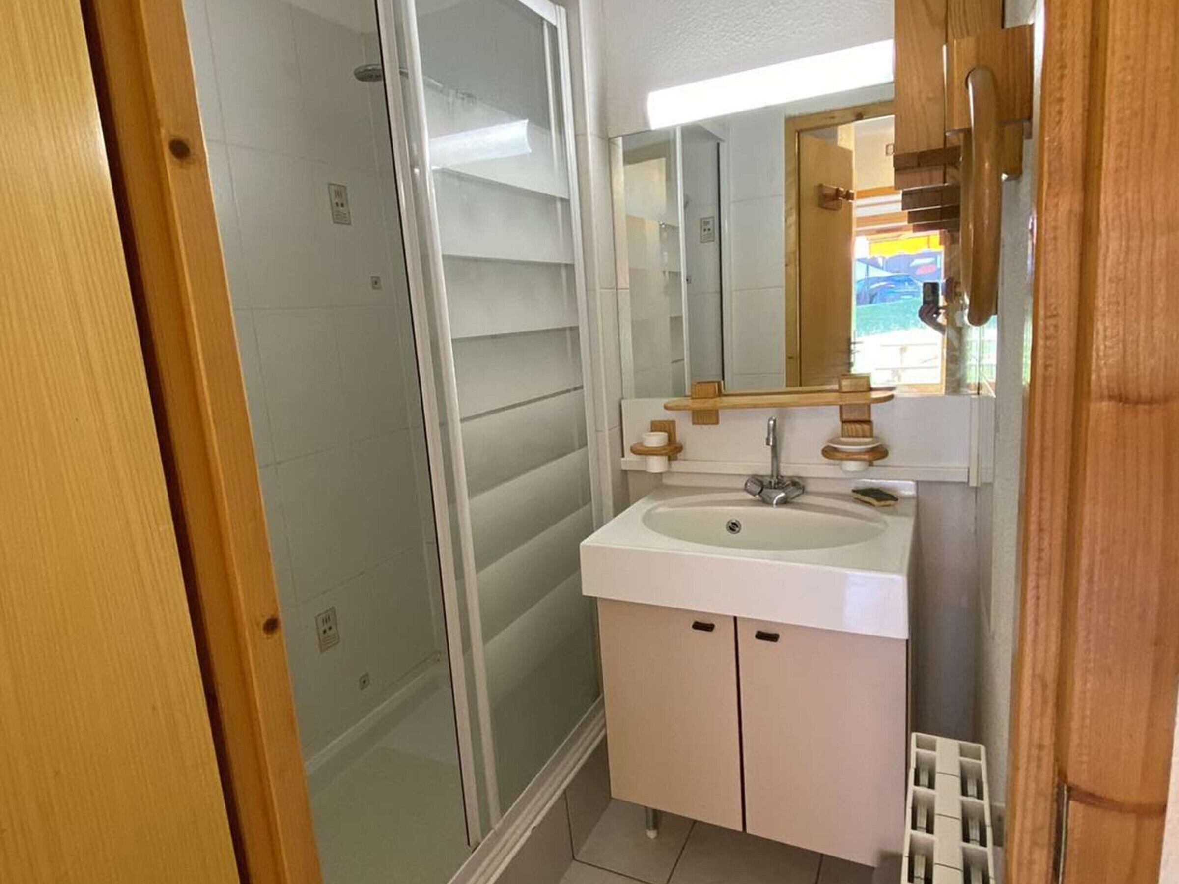 Une salle de bain avec une douche à parois de verre, un lavabo blanc et un miroir au-dessus.