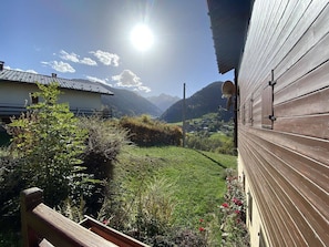 Ein Holzbauten mit einem Balkon, der auf ein grünes Tal und Berge blickt.