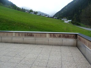 Eine gepflasterte Terrasse mit Blick auf einen grünen Hügel und Häuser.