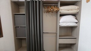 Vaatehuone, jossa on hyllyjä, tilaa vaatteiden ripustamiseen ja seinään taitettava sänky.