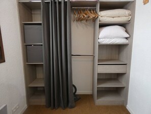 Ein begehbarer Kleiderschrank mit Regalen, Kleiderstangen und einer ausklappbaren Bettliege.