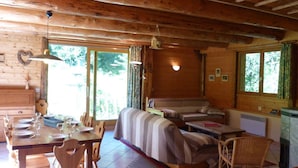 Un intérieur de chalet chaleureux avec un coin repas, un canapé et un téléviseur.