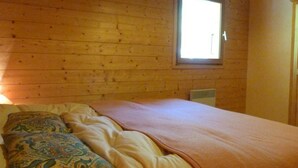 Une pièce de cabane en bois comprenant un lit, une fenêtre et un radiateur.