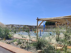 Ein Außenbereich mit einer Holzpergola, Fitnessgeräten und einem befestigten Untergrund.