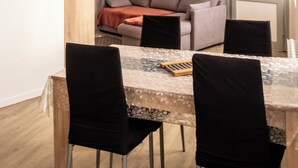 Un comedor con una mesa, sillas, una lámpara colgante, un sofá y una puerta.