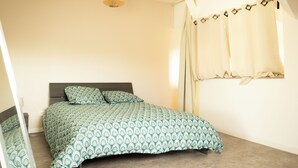 Un dormitorio con cama, lámpara colgante y ventana con cortinas.