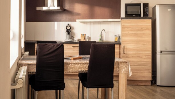 Una cocina moderna con una mesa de comedor, sillas, microondas y refrigerador.