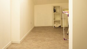 Una habitación con techo inclinado, piso alfombrado y una estantería en la pared.