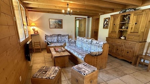 A cozy wooden interior with a sofa, two wooden chests, a cabinet, and a painting on the wall.