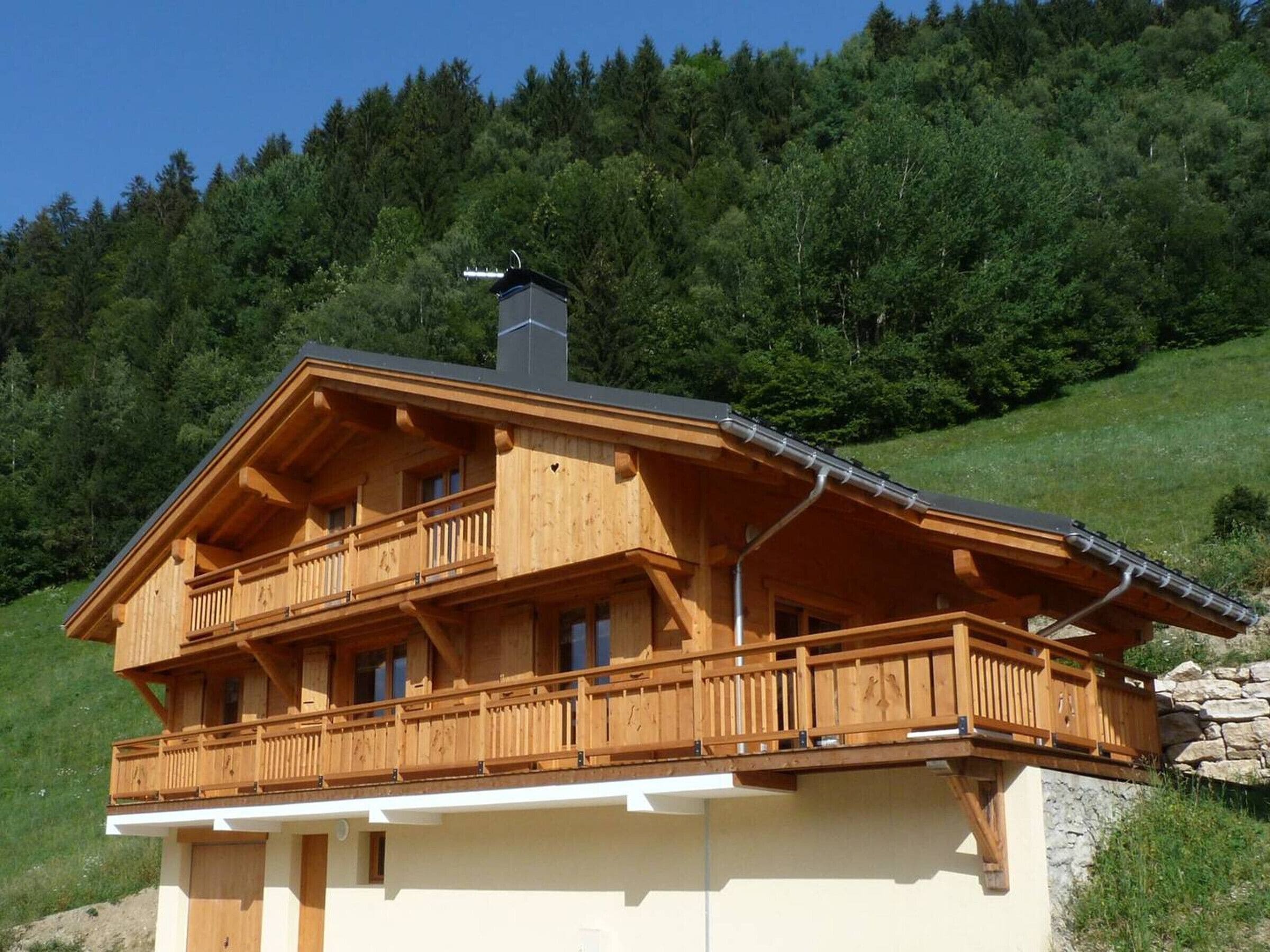 Eine Holzhütte mit Balkon, Schornstein und Steinunterbau.
