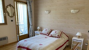 Ein Schlafzimmer mit einem Bett, Nachttischen, einem Spiegel und einem Fenster mit Vorhängen.