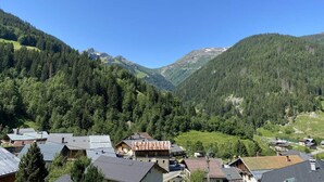 Ein Bergdorf mit traditionellen Häusern, einem Tal und einem Gebirgszug.