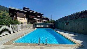 Ein rechteckiger Swimmingpool mit Sprungbrett in der Mitte, umgeben von einer Betonplattform.