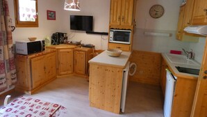 Eine kleine Küche mit Holzschränken, einer Mikrowelle, einem Toaster und einem Spülbecken.