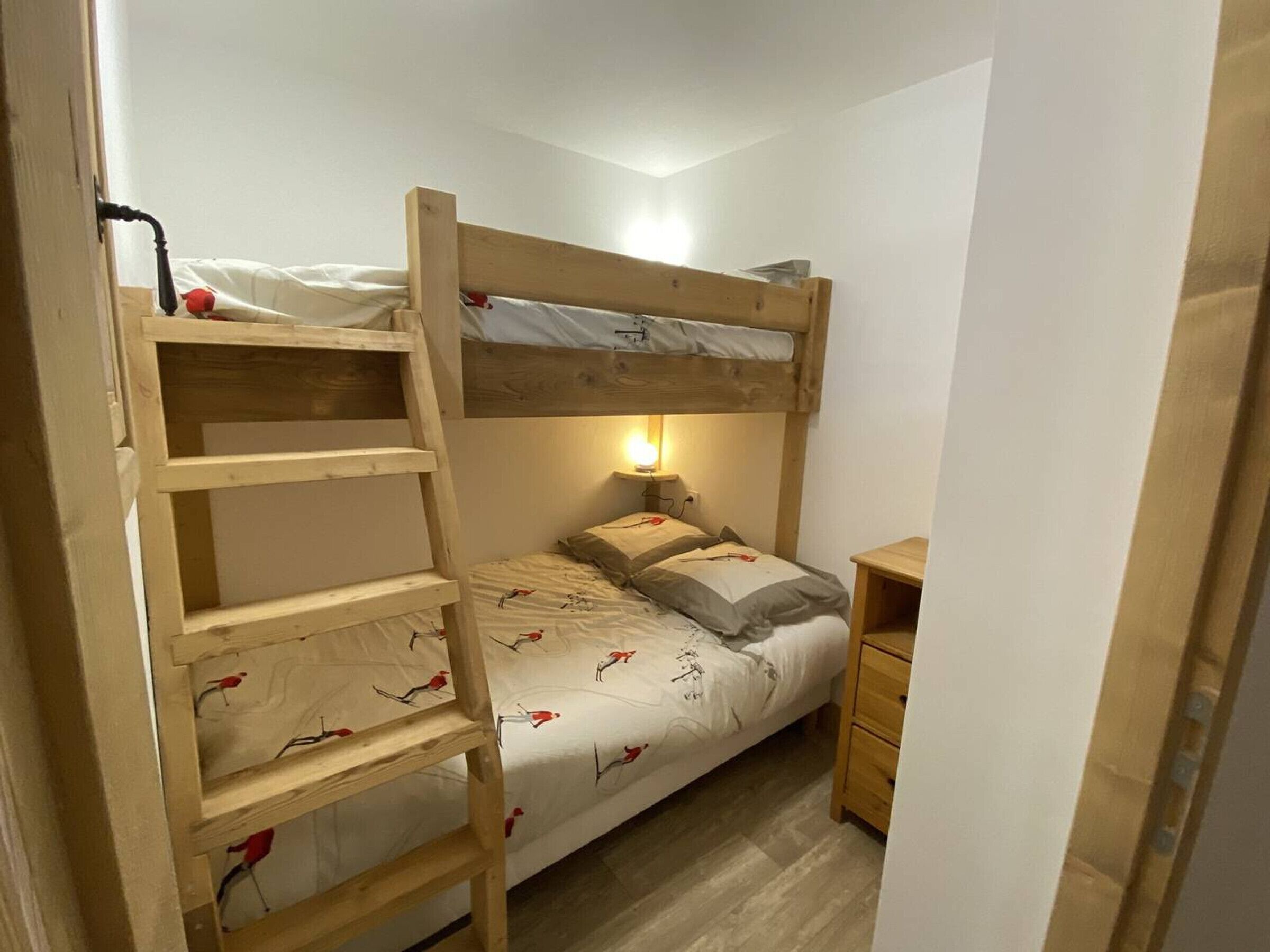 Una litera con una escalera, una mesita de noche y una lámpara.