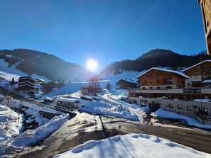 A snow-covered mountain town with buildings, a clear sky, and the sun shining.