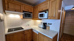 Una cocina compacta con armarios de madera, microondas, tostadora y cafetera.