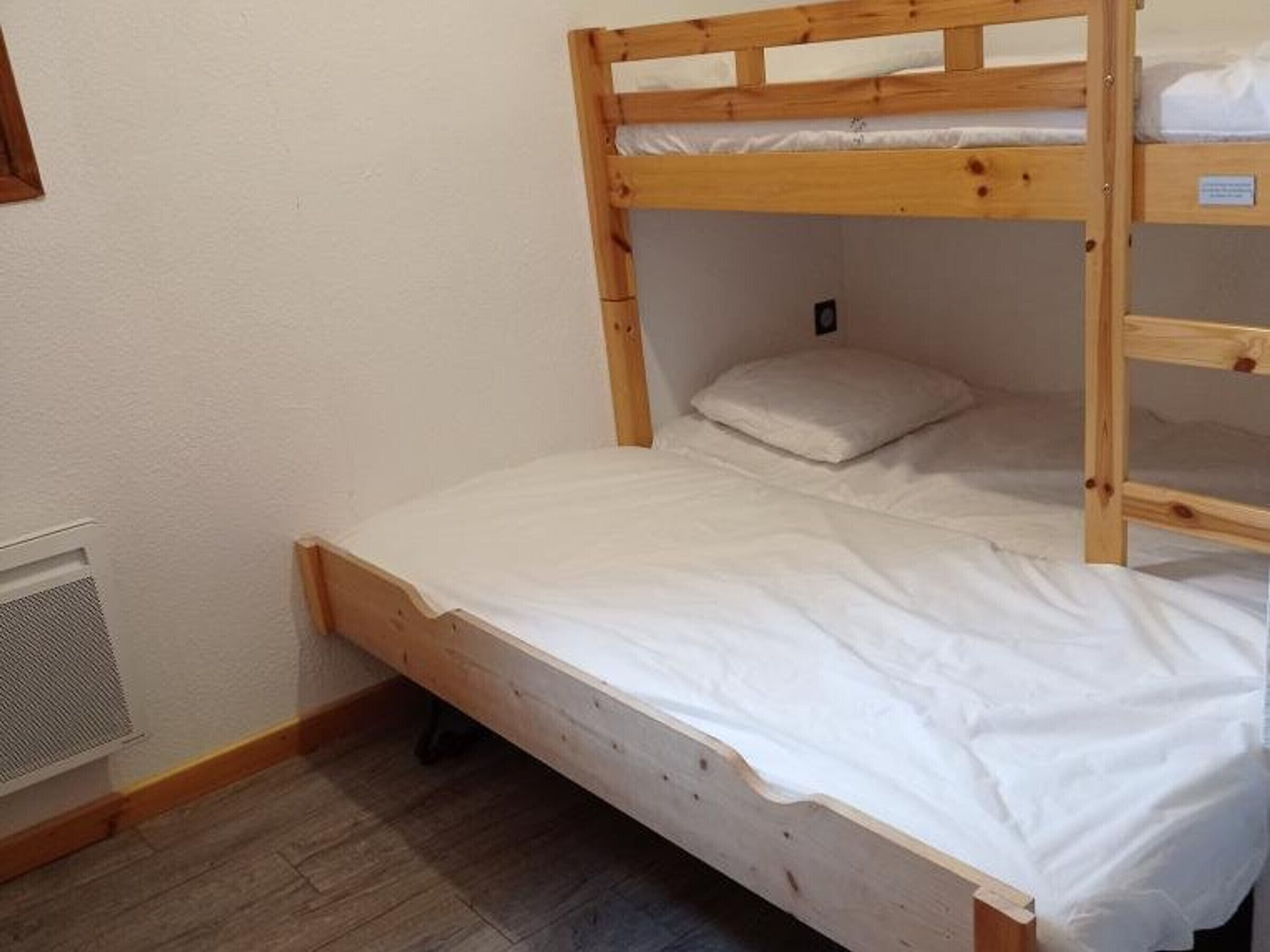 A bunk bed with a white mattress and a wooden frame.