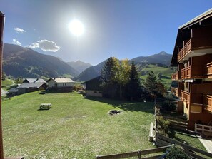A view of a mountainous area with a clear sky, a wooden building with balconies, and a grassy field with a picnic table. - Apartment, pets welcome - 5 guests (Arêches-Beaufort)