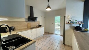 A modern kitchen with a black range hood, a coffee maker, and a sink. - Oliveta Vacation Rental (Palaja)