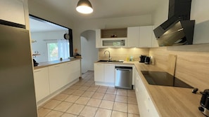 A modern kitchen with white cabinets, a stainless steel dishwasher, a microwave, and a black range hood. - Oliveta Vacation Rental (Palaja)