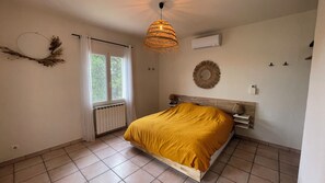 A bedroom with a bed, a window with curtains, a wall-mounted air conditioner, a wall-mounted mirror, and a ceiling light fixture. - Oliveta Vacation Rental (Palaja)