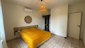 A bedroom with a bed, a wall-mounted air conditioner, a woven light fixture, a mirror, and a door. - Oliveta Vacation Rental (Palaja)