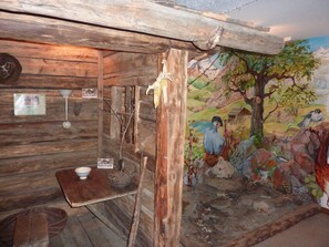A rustic cabin interior with wooden walls, a mural of a landscape, and a small table with a bowl. - T2 apartment, pets allowed, village view (Arêches-Beaufort)