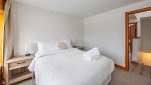 A hotel room with a bed, bedside tables, a lamp, and a mirror. - Suite 8 at The Gem | Scenic Canmore Getaway (Harvie Heights)