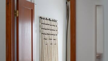A hallway with a wooden door, a macrame wall hanging, and a mirror on the wall.
