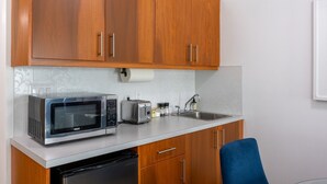 A compact kitchen with wooden cabinets, a microwave, a toaster, and a sink. - Suite 8 at The Gem | Scenic Canmore Getaway (Harvie Heights)