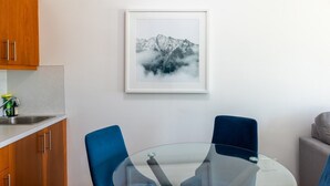 A modern kitchen with wooden cabinets, a stainless steel sink, and a blue chair at a glass table. - Suite 8 at The Gem | Scenic Canmore Getaway (Harvie Heights)