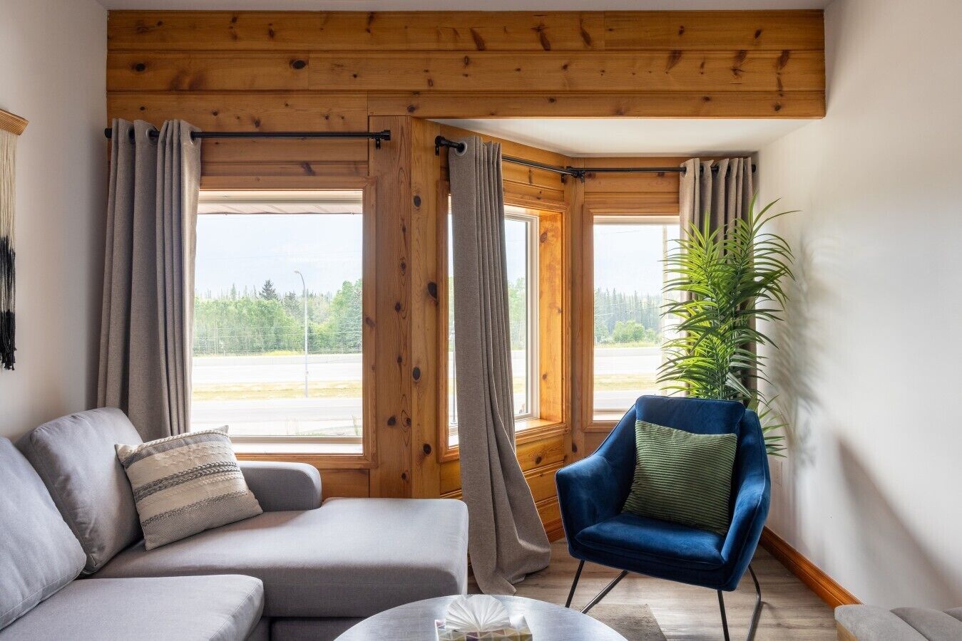 A cozy room with a sofa, a blue armchair, and a large window with curtains.