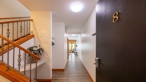 A hallway with a wooden staircase, a door with a number, and a plant on the wall. - Suite 8 at The Gem | Scenic Canmore Getaway (Harvie Heights)