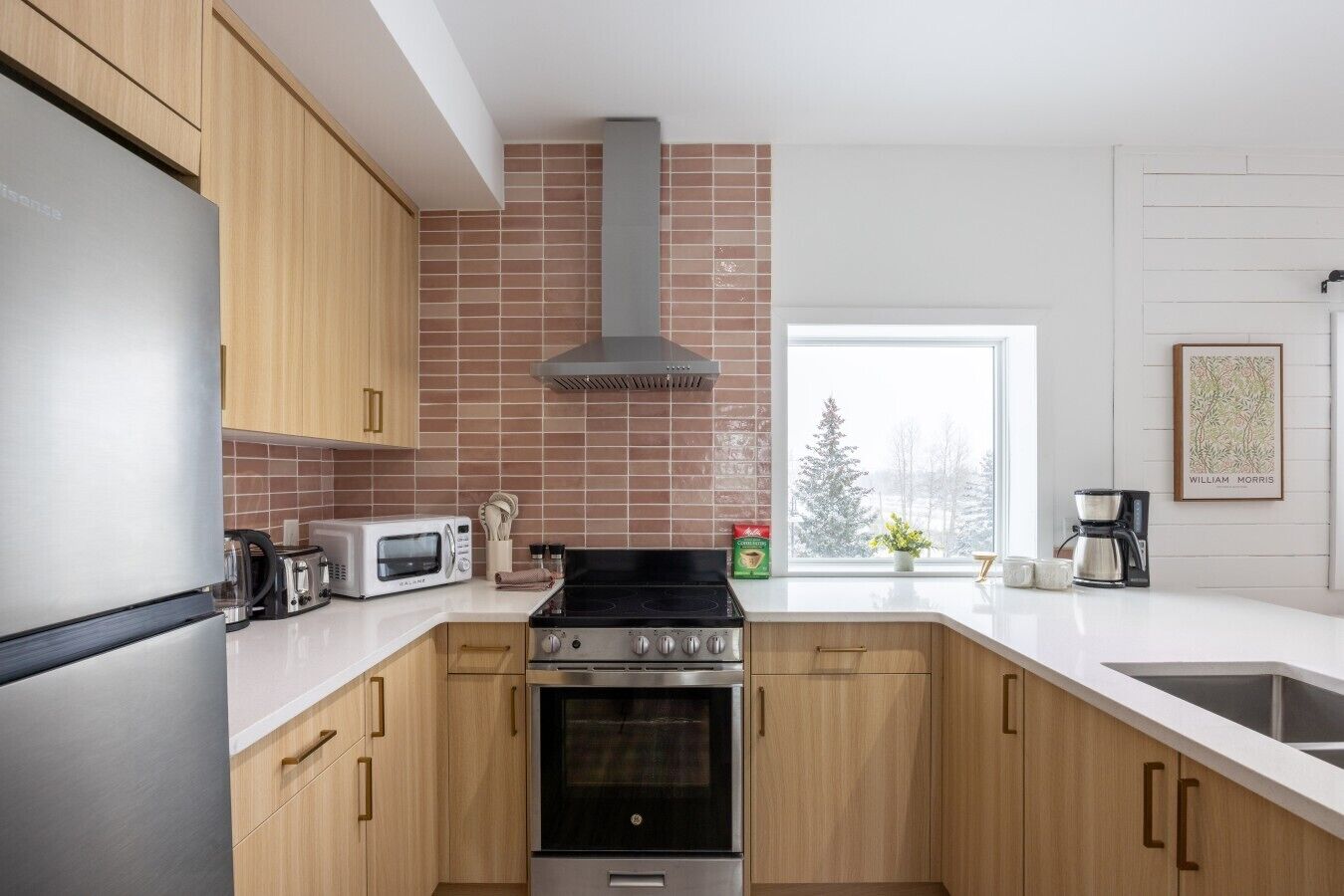 A modern kitchen with wooden cabinets, a stainless steel range, a built-in oven, a microwave, and a coffee maker.