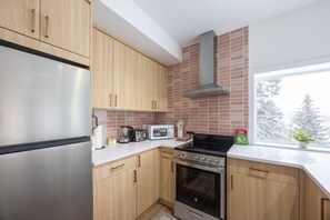 Una cocina moderna con electrodomésticos de acero inoxidable, armarios de madera y un amplio ventanal con vistas a árboles.
