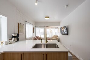 A modern kitchen with a large island, a coffee maker, and a bottle of hand soap. - The Ruby Suite | Premium Rocky Mountain Retreat (Harvie Heights)