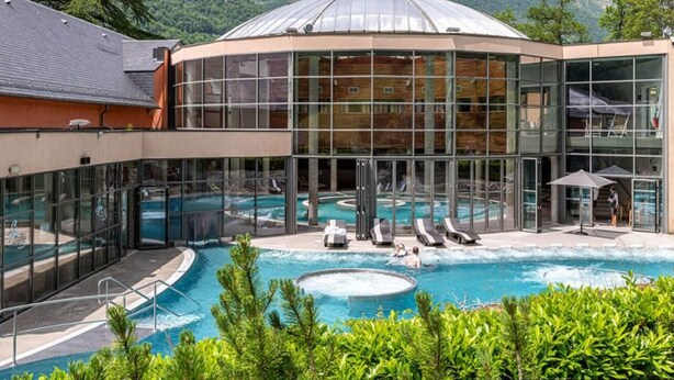A hotel with a glass-enclosed pool, lounge chairs, and a view of mountains. - Modern T2, central, near cable cars (Cauterets)