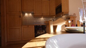 A kitchen with wooden cabinets, a microwave, and a dining table with a glass and plates. - Cozy apartment - 6 guests (Arêches-Beaufort)