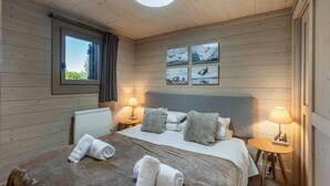 A cozy room with a bed, two bedside tables, a window, and wall art. - Family apartment, balcony - 6 guests (Méribel)