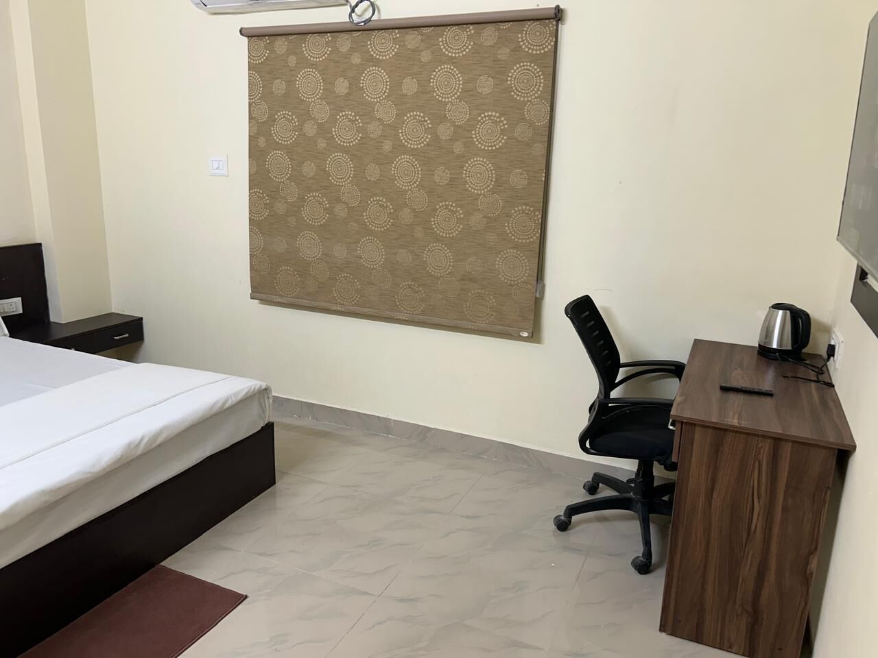 A bedroom with a bed, a desk, a chair, and a curtain.