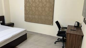 A bedroom with a bed, a desk, a chair, and a curtain.
