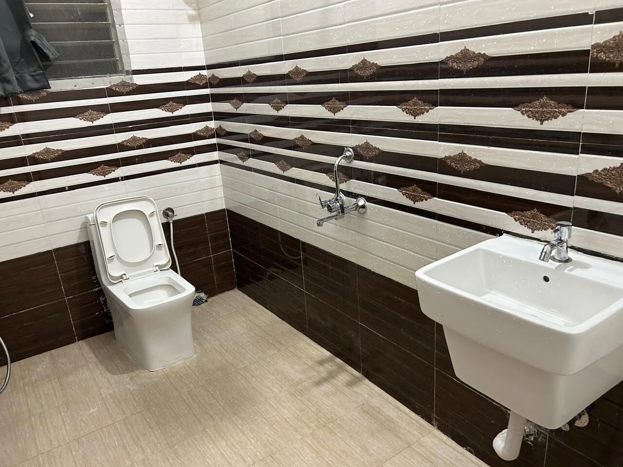 A bathroom with a toilet, sink, and tiled walls.