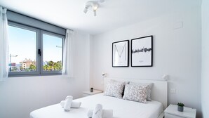 A modern hotel room with a large bed, two framed pictures on the wall, a bedside table with a plant, and a window with curtains. - Duna Beach Torrox Costa by Casasol (Torrox Costa)