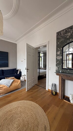 Ein Zimmer mit einer Couch, einem runden Teppich, einer Tür zu einem anderen Raum und einem Kamin.