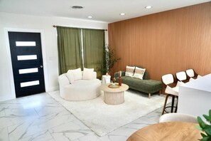 Ein modernes Wohnzimmer mit einer Couch, einem runden Couchtisch und einer grünen Akzentwand.